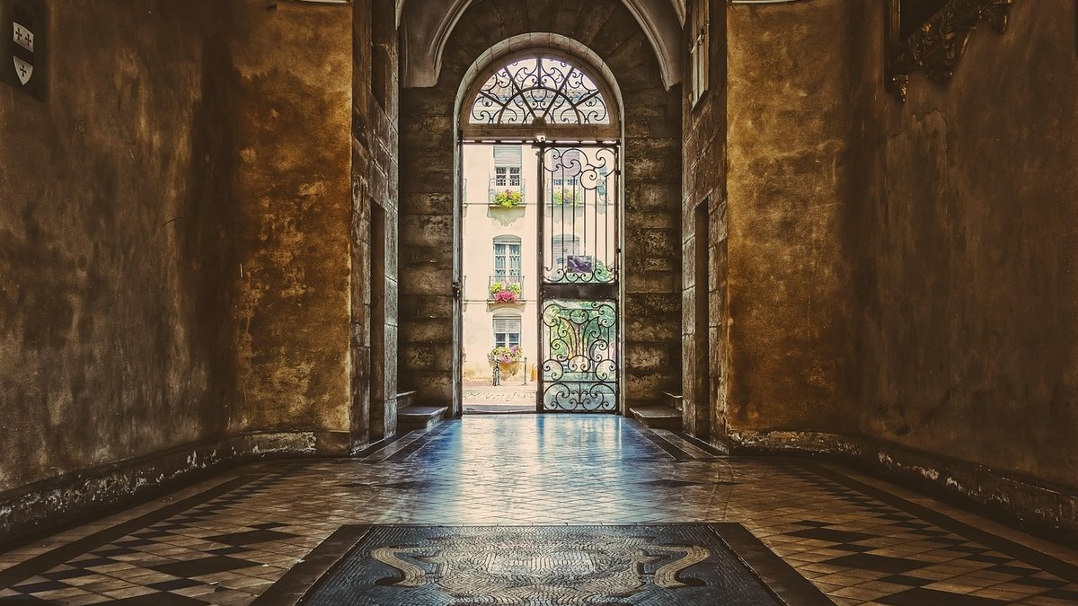 Porche d'un immeuble ancien avec sol en mosaïque et grille en fer forgé - Estimation immobilière Voiron